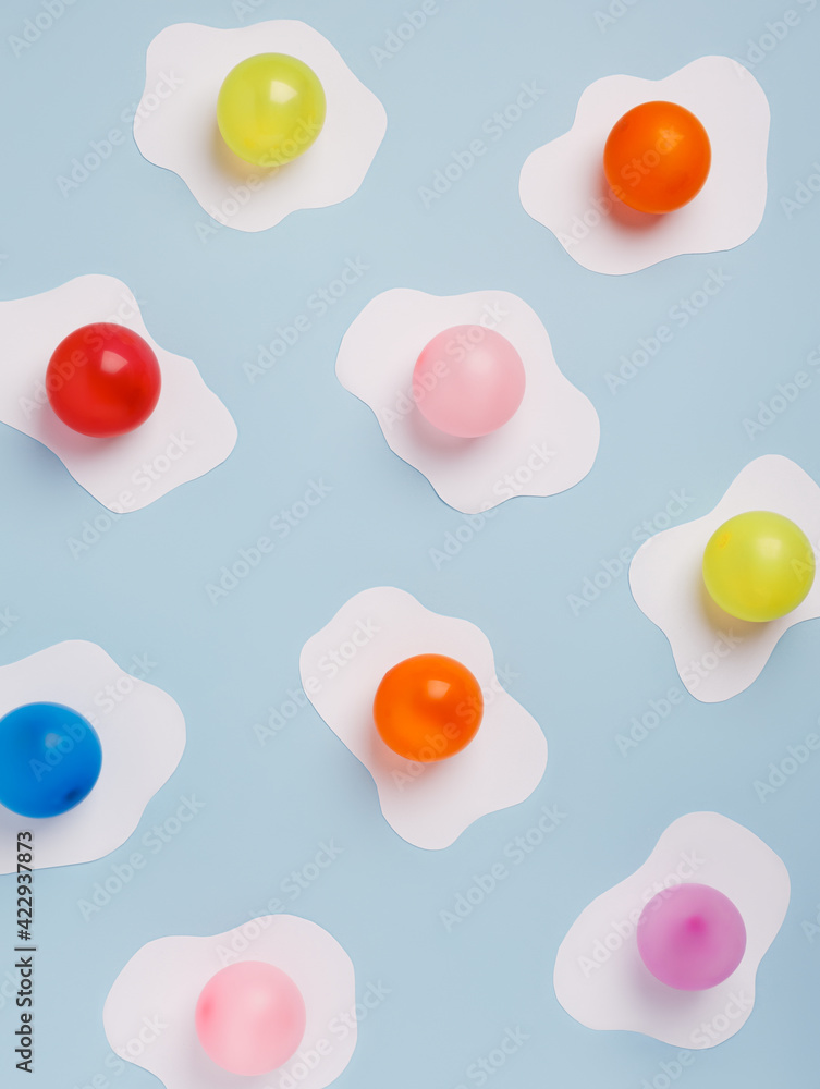 Fried eggs with multicolor yolks pattern made of paper on a pastel blue background. Minimalistic food fashion concept. Flat lay, top view.