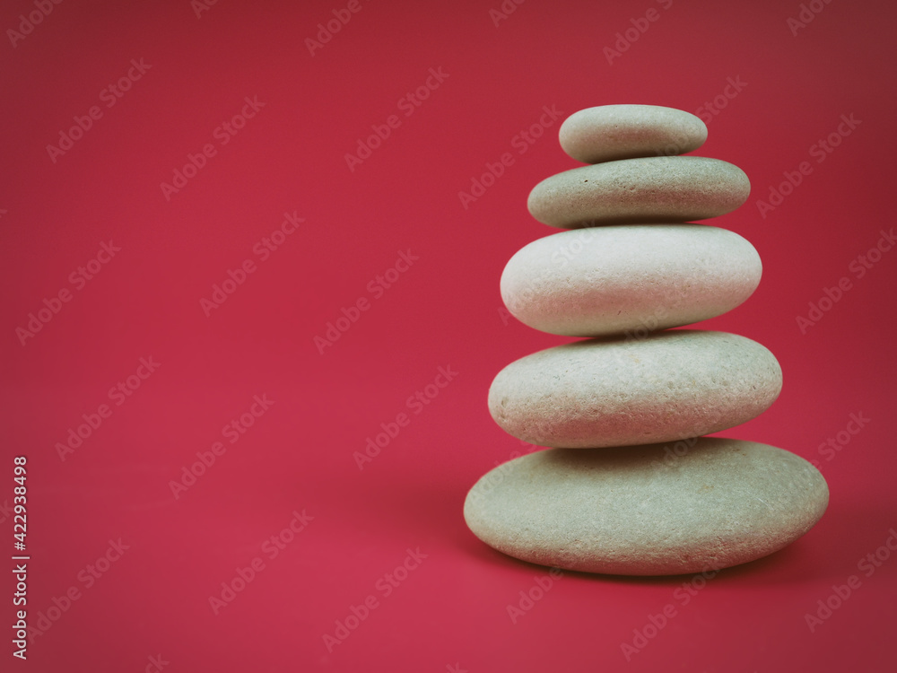 A stack of white zen stones on a pink background, minimalism