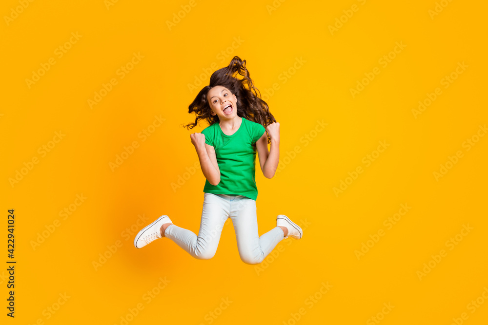 Full size photo of happy excited crazy good mood screaming girl jumping in triumph isolated on yellow color background Full size photo of happy excited crazy good mood screaming girl jumping in triumph isolated on yellow color background