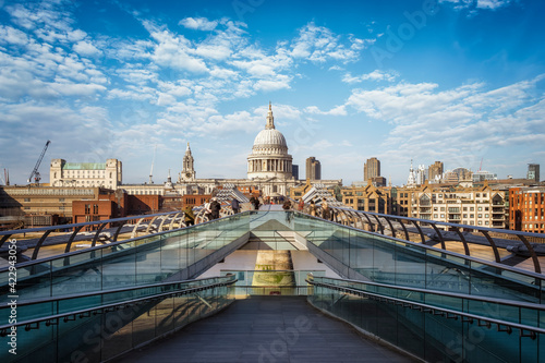 Perspective view to the skyline of London, United Kingdom, with St. Pauls Cathedral and blurred people walking during a sunny spring day