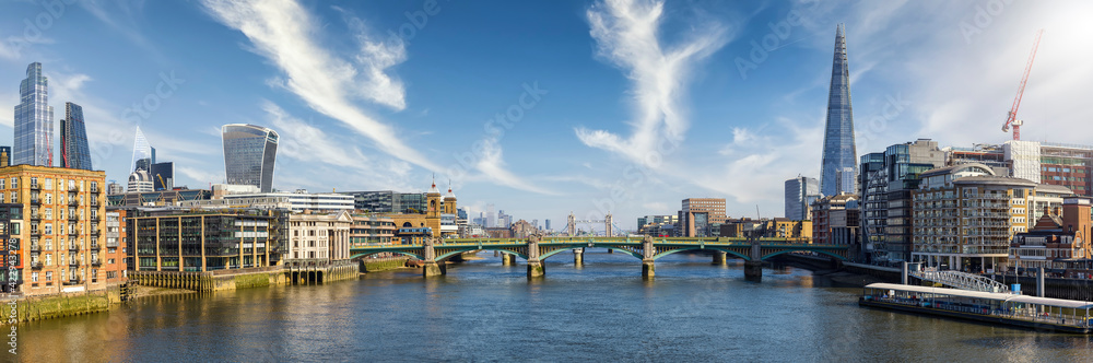 Panoramic view of the London skyline along the Thames river with Southwark Bridge and Tower Bridge during a sunny day