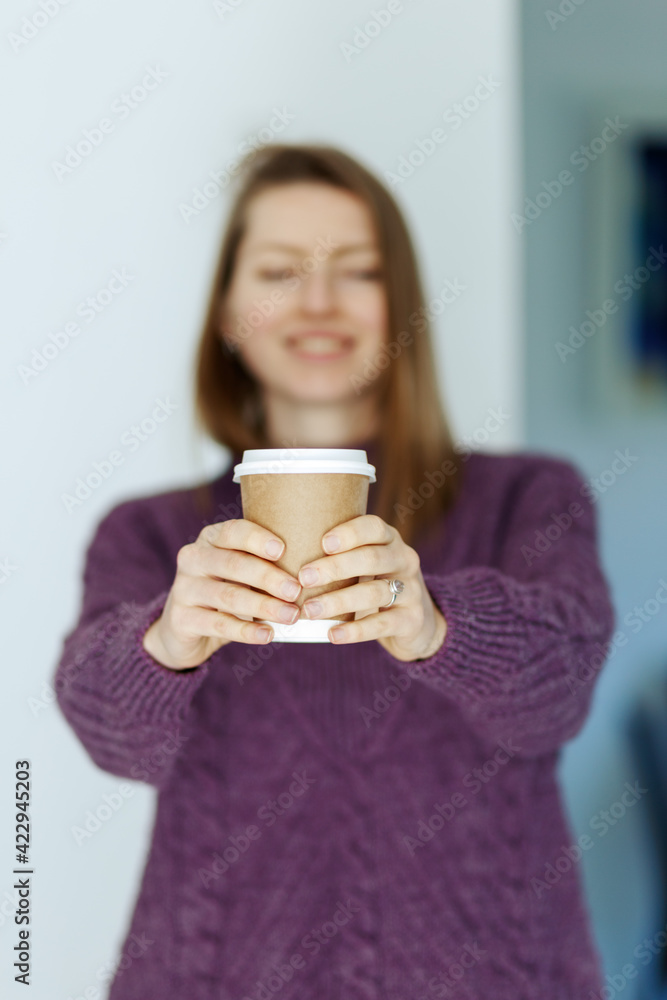 Soft focus pretty young woman in stylish violet sweater holding cup in hands. Warm soft cozy image. Details. Drinking take away coffee. Breakfast on the go. Instagram style toned image. Focus on cup Soft focus pretty young woman in stylish violet sweater holding cup in hands. Warm soft cozy image. Details. Drinking take away coffee. Breakfast on the go. Instagram style toned image. Focus on cup