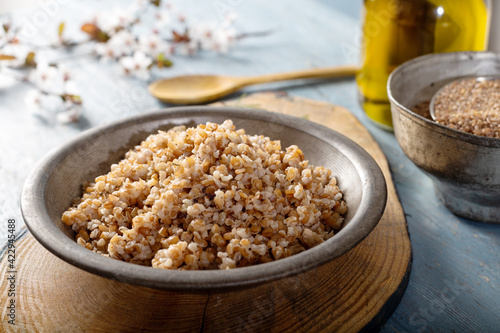 Einkorn, Triticum Monococcum, Siyez wheat bulgur.Bulgur pilaf made with siyez bulgur in plate on wooden background. photo