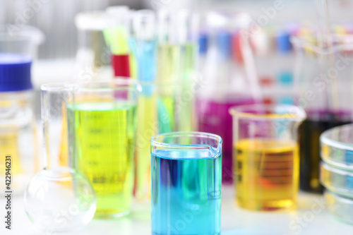 Flasks and test tubes with multicolored liquid standing on table in laboratory