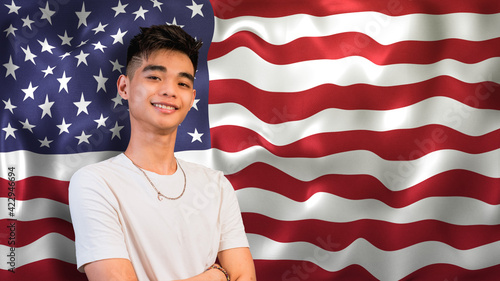 A proud young Asian American man, in front of a waving US flag. photo