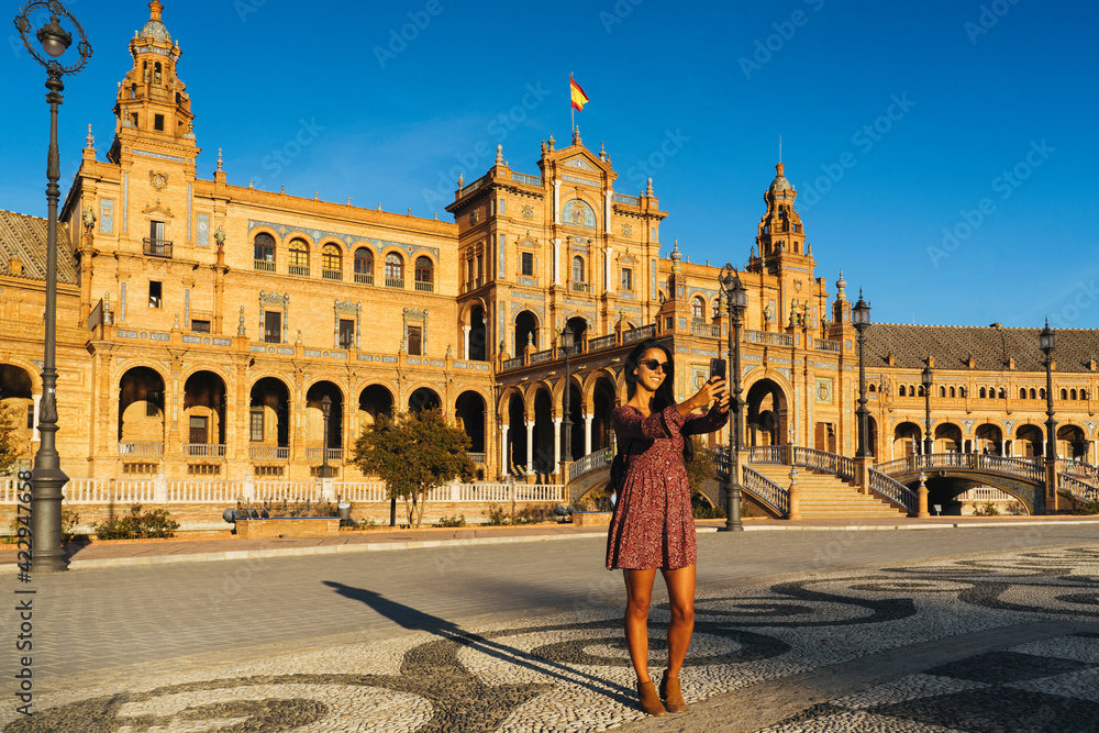 Young and cool woman making selfie with smartphone in Spain Square, Seville.