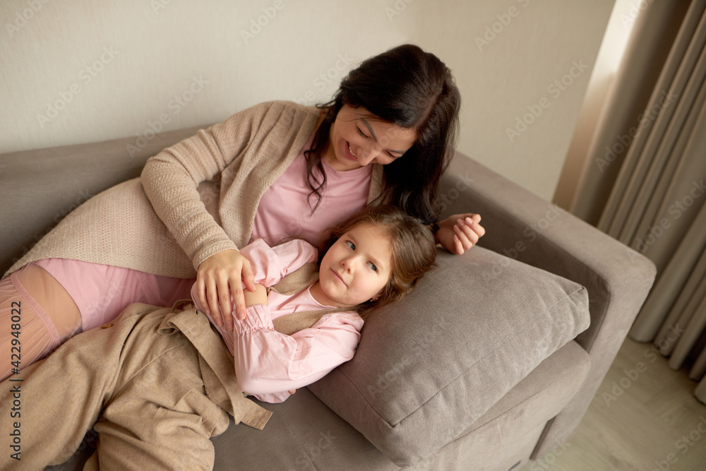 daughter is offended by mom. mom and daughter lie on the couch and mess around or fool around