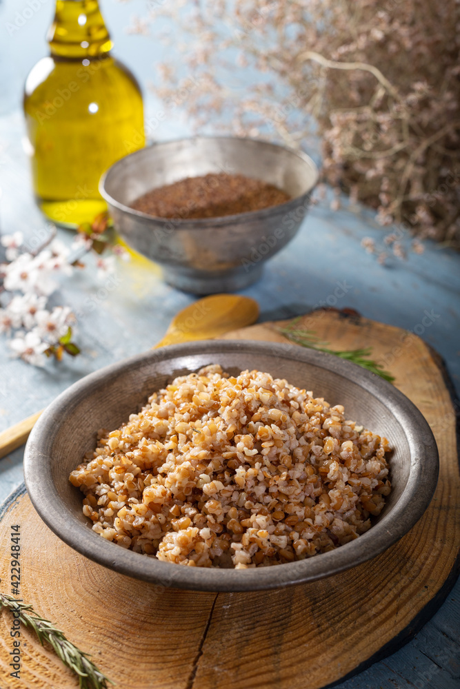 Einkorn, Triticum Monococcum, Siyez wheat bulgur.Bulgur pilaf made with siyez bulgur in plate on wooden background. Einkorn, Triticum Monococcum, Siyez wheat bulgur.Bulgur pilaf made with siyez bulgur in plate on wooden background.