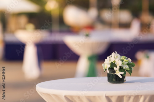 a glass vase with flowers on the white reception table at beachfront weddings party even
