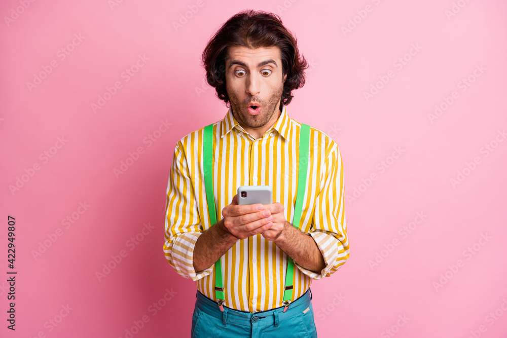 Photo of young handsome shocked amazed surprised man uses smartphone see sms isolated on pink color background Photo of young handsome shocked amazed surprised man uses smartphone see sms isolated on pink color background