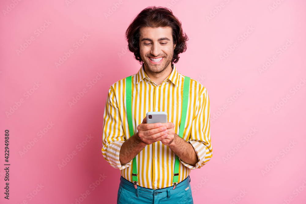 Photo of young happy smiling cheerful positive good mood man using smartphone isolated on pink color background Photo of young happy smiling cheerful positive good mood man using smartphone isolated on pink color background