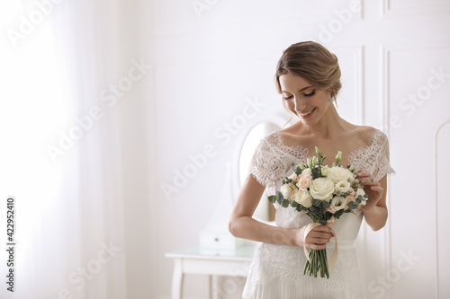 Bride in beautiful wedding dress with bouquet indoors. Space for text
