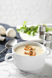 Delicious cream soup with mushrooms on white marble table