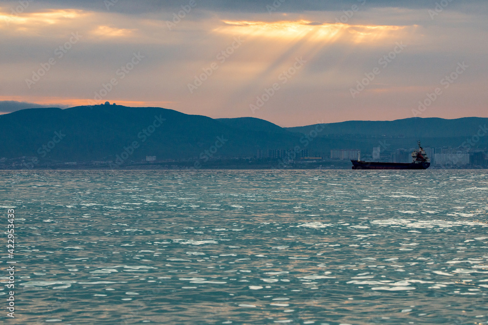 Beautiful sunset amongst the clouds. The sun rays are simply beautiful. City, mountains and ship in sea Beautiful sunset amongst the clouds. The sun rays are simply beautiful. City, mountains and ship in sea