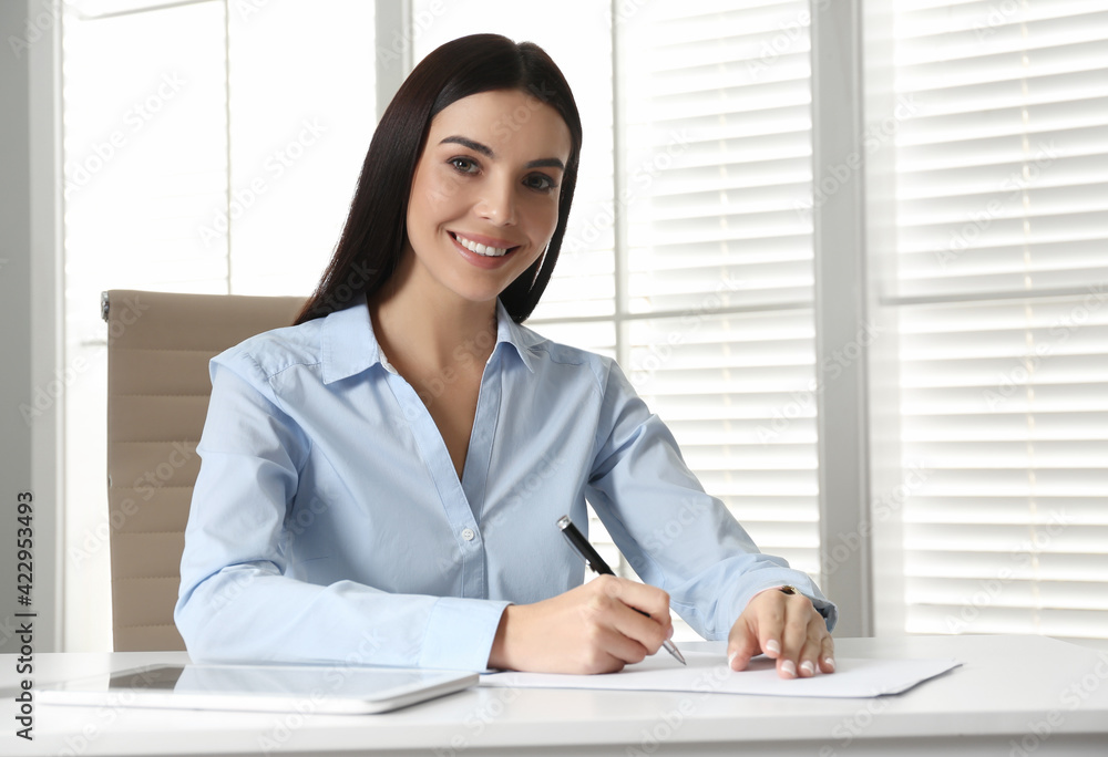 Young businesswoman writing at table in office Young businesswoman writing at table in office