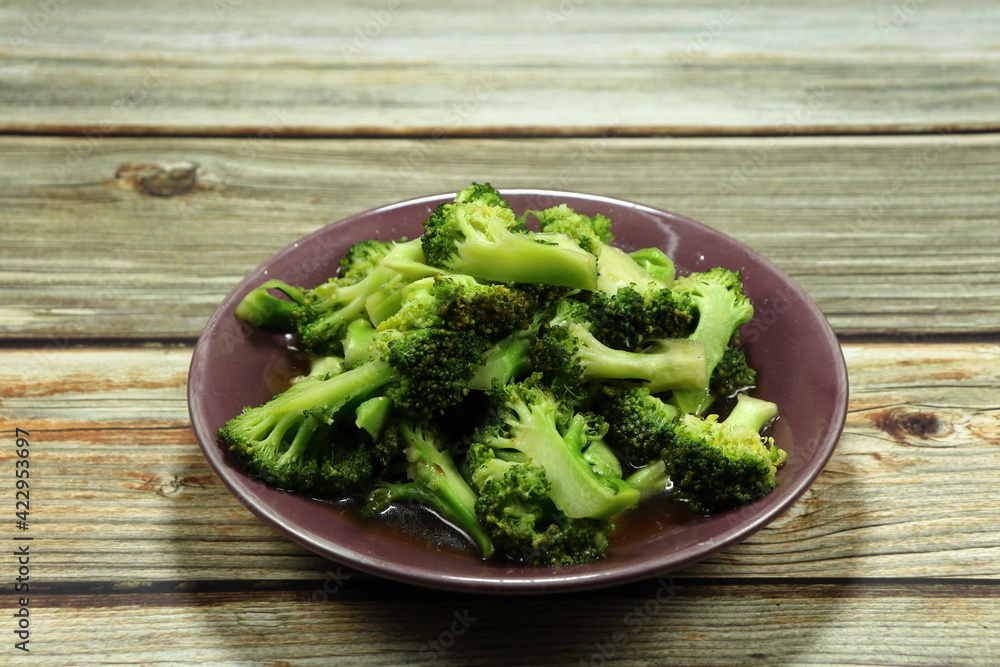 Traditional fried and stirred fresh broccoli seasoning with soy sauce and pepper serving on the plate. Famous vegetarian menu in Asia restaurant. 
