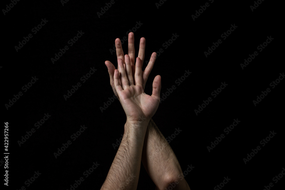 Male hands on a black background. Two male hands on a dark background. Body parts.