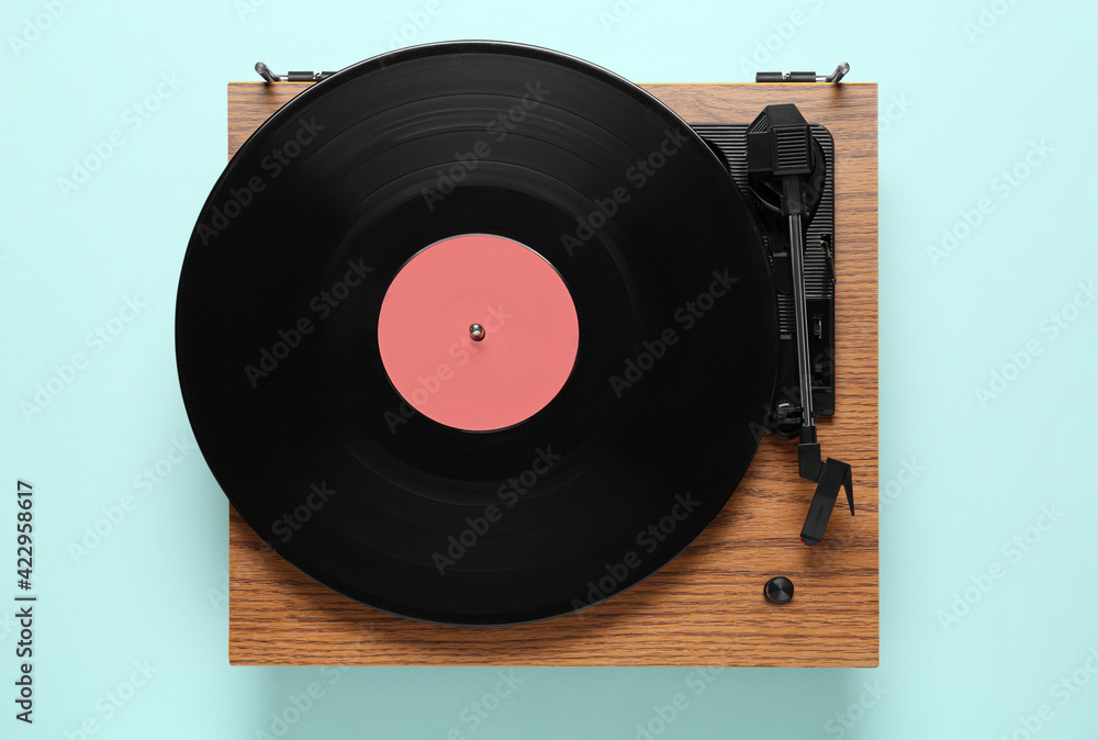 Obraz premium Modern turntable with vinyl record on light blue background, top view