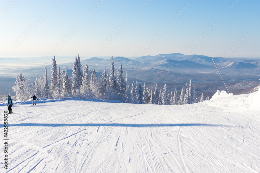 ski trail with snowy mountains and trees are covered with white fluffy snow in sunny day