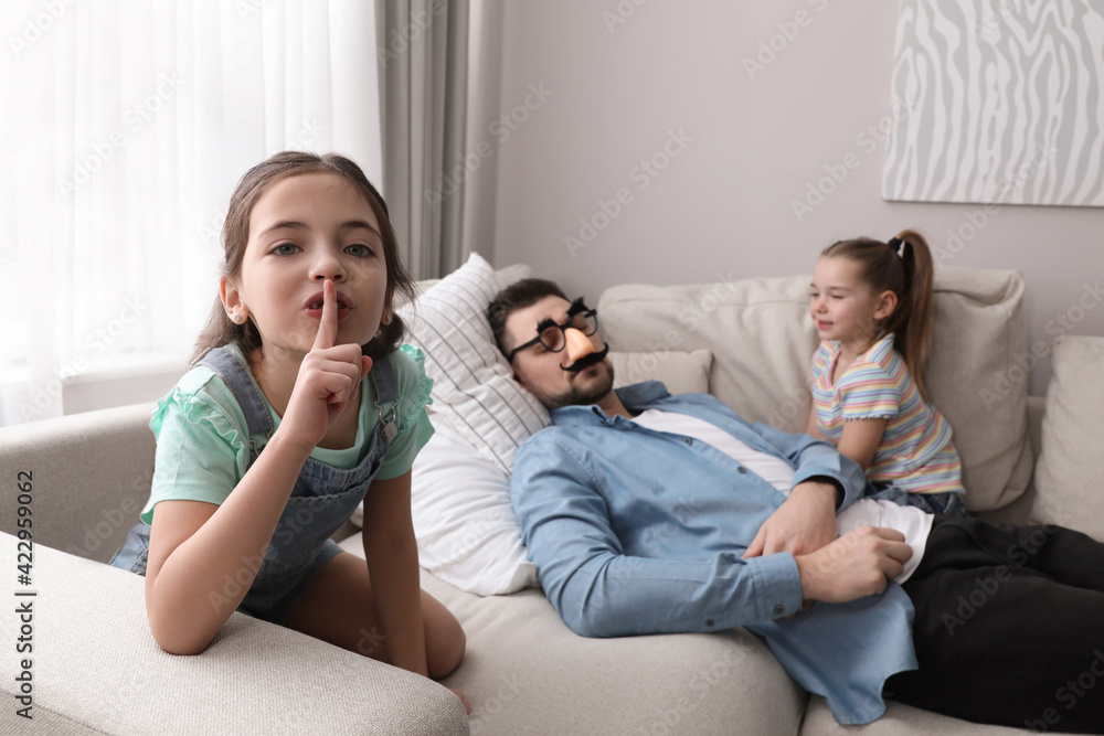 Cute little children putting funny glasses on father while he sleeping at home Cute little children putting funny glasses on father while he sleeping at home