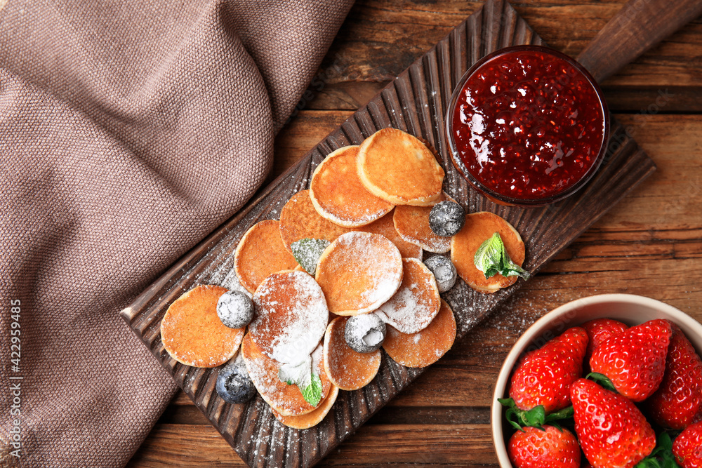 Cereal pancakes with jam and berries on wooden table, flat lay Cereal pancakes with jam and berries on wooden table, flat lay
