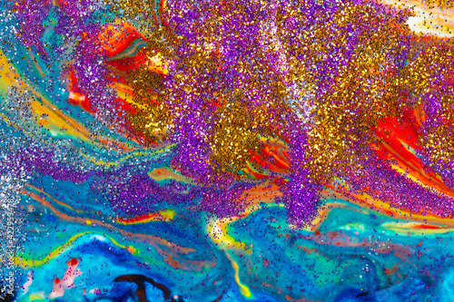 Multicolored acrylic backdrop sprinkled with purple and gold sequins. Contemporary creativity. A colorful avant-garde painting with rich texture. A background made up of many shapes and materials.