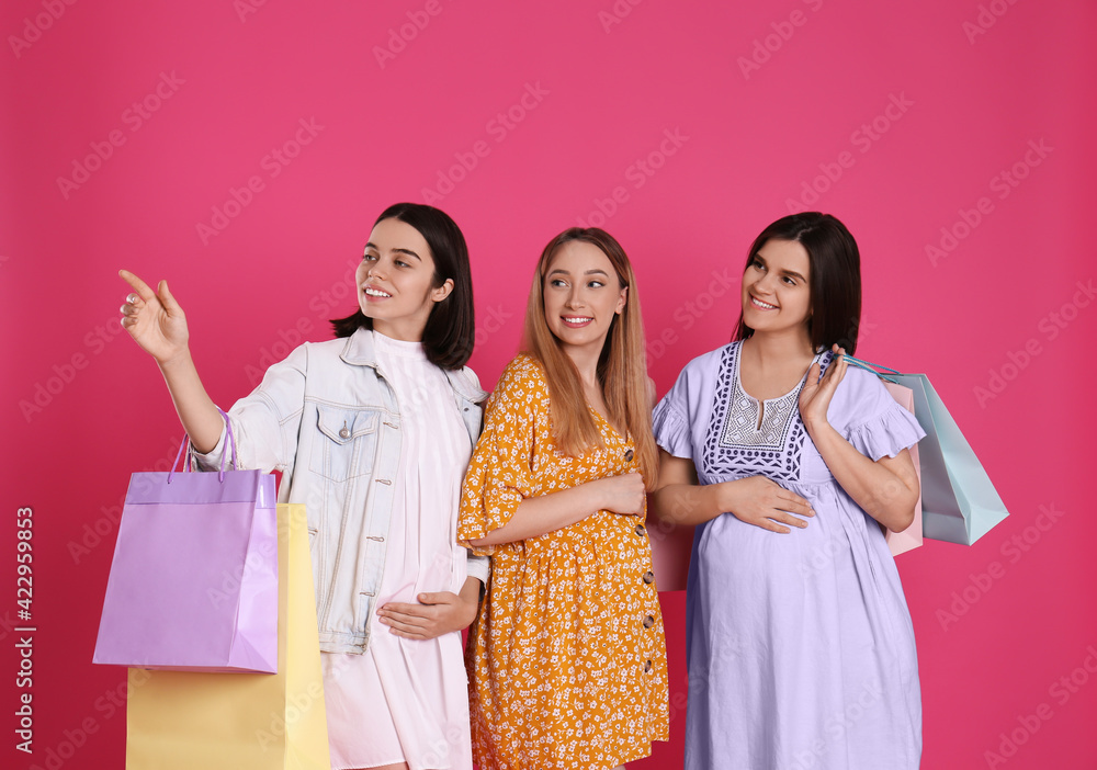 Happy pregnant women with shopping bags on pink background Happy pregnant women with shopping bags on pink background