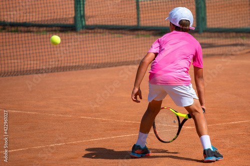 a boy in a pink t-shirt and white shorts is playing tennis © Павел Мещеряков