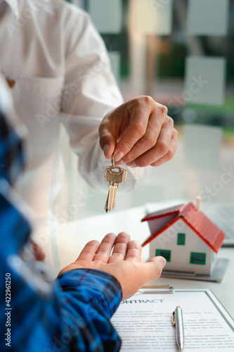 The insurance agent handed over the house key to the customer who agreed to buy the house after negotiating and concluding the contract. Mortgage loan approval home loan and insurance concept.