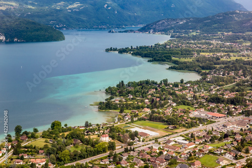 View of the Annecy lake surrounded of mountains  with cityscape in cloudy weather. Rhone Alps, France.