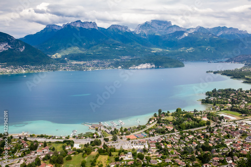 View of the Annecy lake surrounded of mountains  with cityscape in cloudy foggy weather. Rhone Alps, France. © Anna