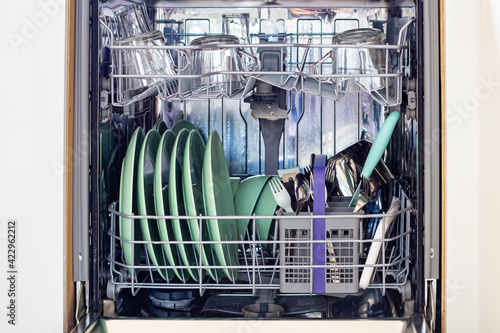 Open dishwasher  with clean glasses and dishes, easy to use and save water, eco friendly.