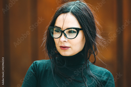 Beauty sexy fashion model woman portrait wearing eye glasses. Elegant woman looking at camera in the black dress with glasses