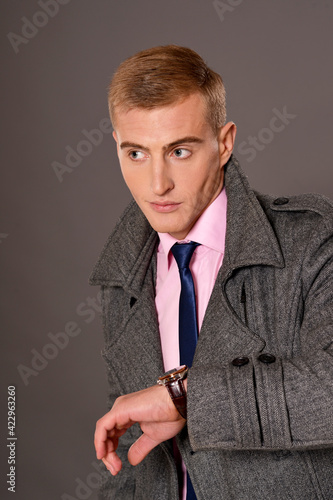 Portrait of young businessman in coat   posing in studio photo