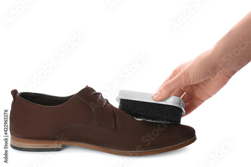 Woman cleaning suede leather shoe on white background, closeup. Footwear care accessory
