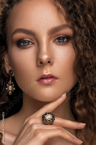 beautiful woman with delicate nude makeup and curly hair. luxury jewelry.