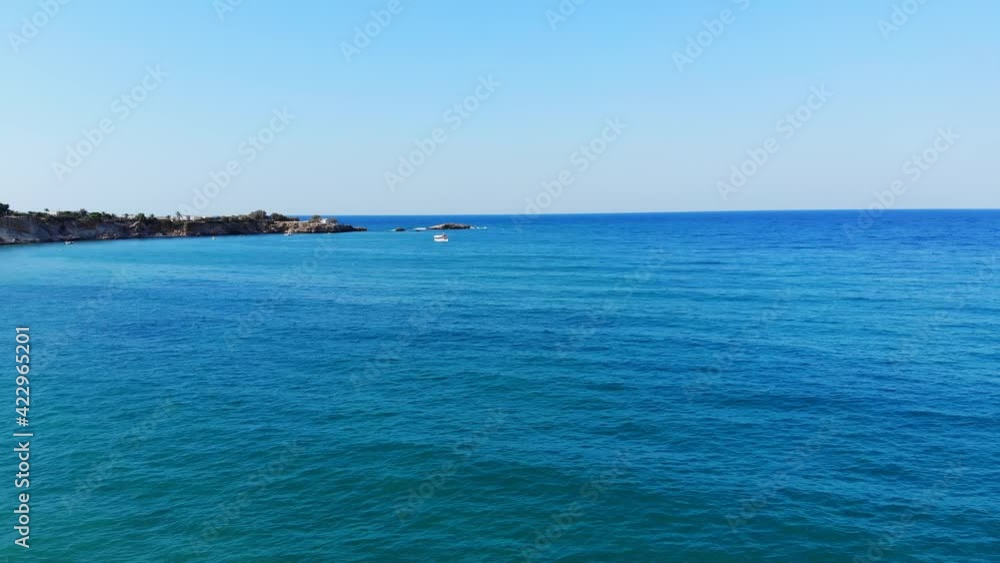 Beautiful green-blue colour of calm Aegean sea, aerial shot. Rocky cape land seen ahead, small tourist boat sail towards. Mellow season time at north shore of Crete Island Beautiful green-blue colour of calm Aegean sea, aerial shot. Rocky cape land seen ahead, small tourist boat sail towards. Mellow season time at north shore of Crete Island