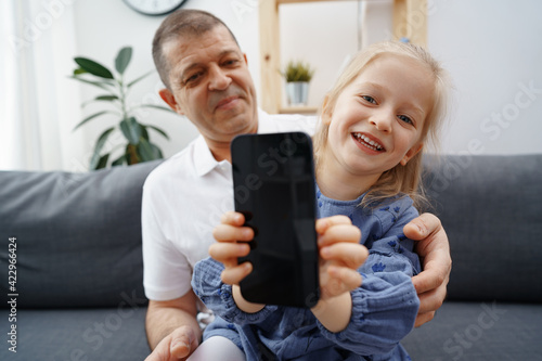 Grandpa and granddaughter showing you black smartphone screen