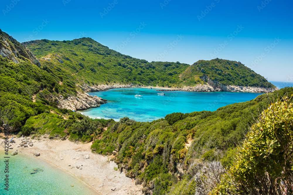 Porto Timoni beach on Corfu island in Greece. Beautiful panoramic view of green mountains, clear sea water, secluded Pirates bay and empty stony beach. Famous destination for summer vacation