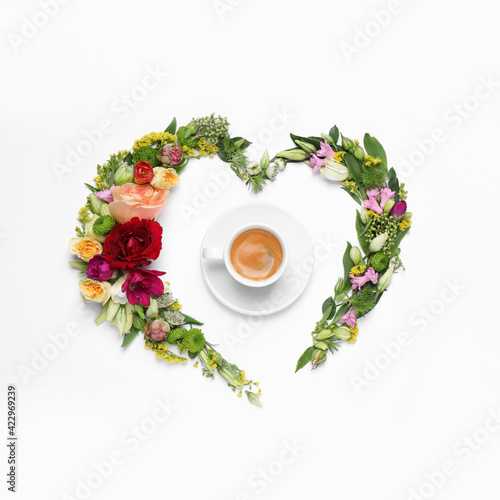 Beautiful heart shaped floral composition with cup of coffee on light background, flat lay