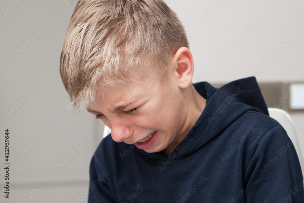 sad hurt little boy is crying with his head down sad hurt little boy is crying with his head down
