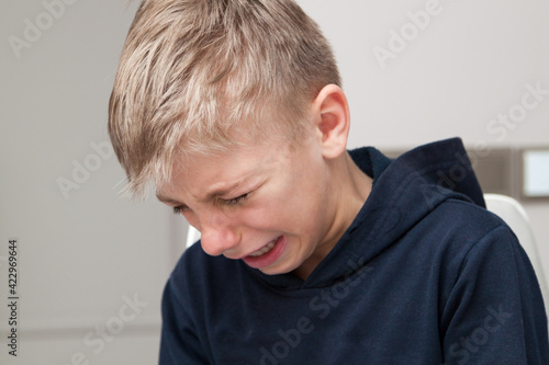 sad hurt little boy is crying with his head down