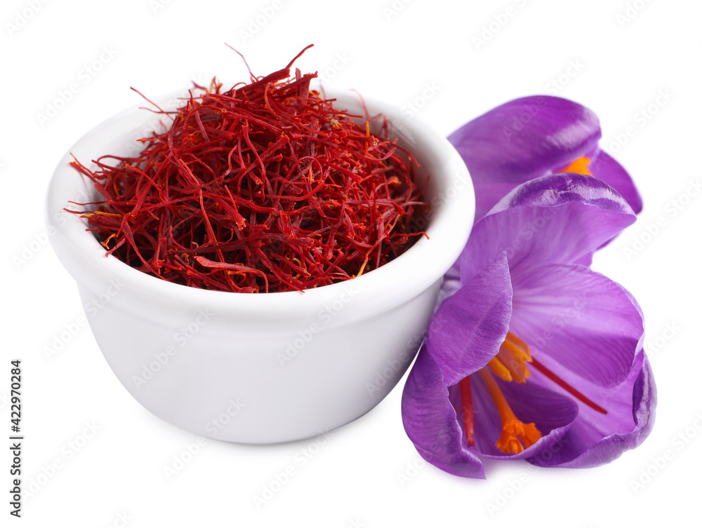 Fototapeta premium Dried saffron in bowl and crocus flowers on white background