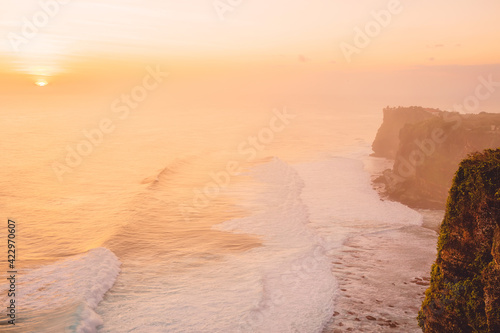 Sunset with ocean, waves and Uluwatu cliff at Bali