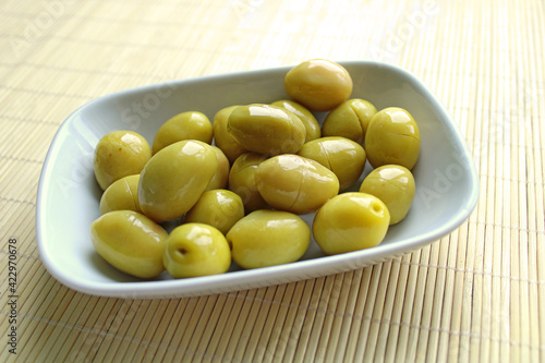 Fresh green olives and olive oil in the plate, wooden background,top view