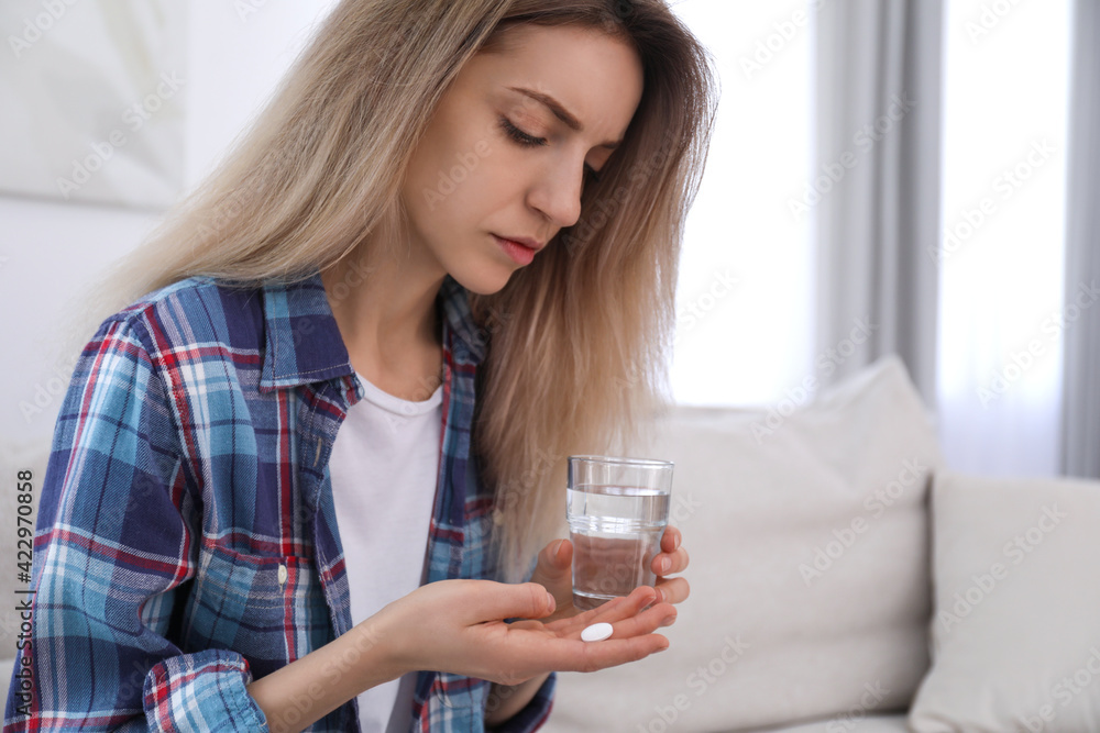 Upset young woman with abortion pill and glass of water at home Upset young woman with abortion pill and glass of water at home