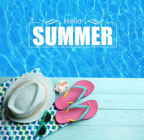 Hello Summer. Beach accessories on light blue wooden deck near swimming pool, flat lay