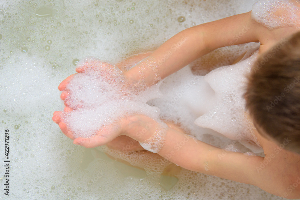 The child is bathing in the bathtub. Foam on hands while bathing. Cleanliness is the key to health. All children really like foam and soap bubbles. The child is bathing in the bathtub. Foam on hands while bathing. Cleanliness is the key to health. All children really like foam and soap bubbles.