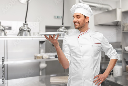 happy smiling male chef holding empty plate