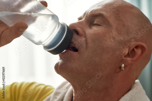 Middle aged caucasian man drinking from sport bottle